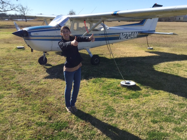 Photo of a female student standing next to a training aircraft